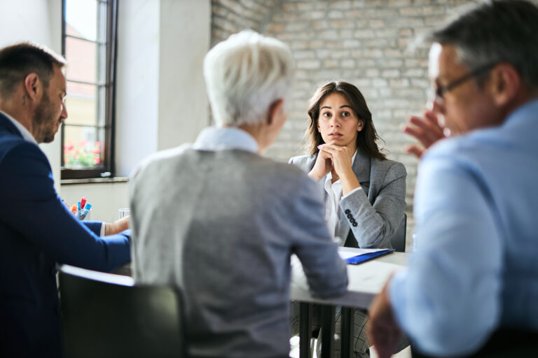 Mature female experiencing auditory neuropathy while at a job interview.