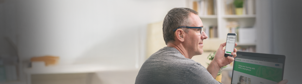 A man using hearing aids with a smartphone