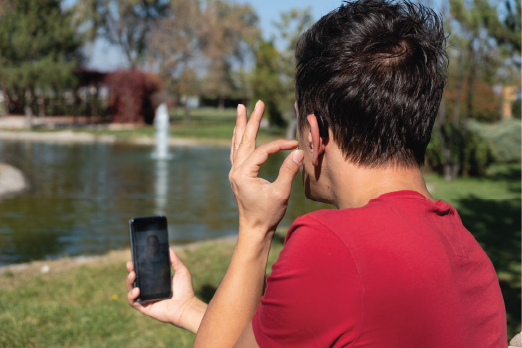 hearing aid pairing with smartphone - Adult male adjusting his hearing aids while sitting in the park.