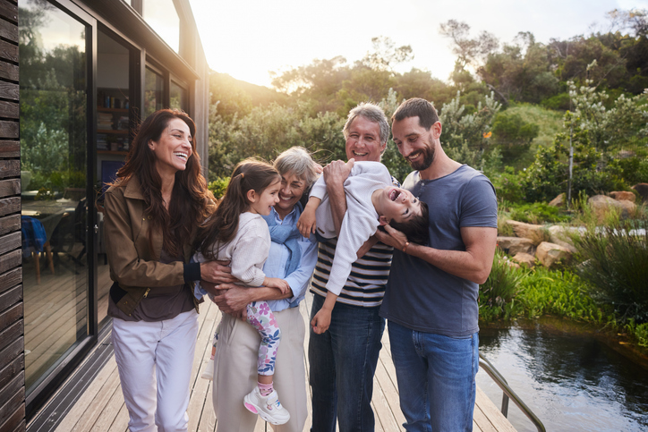 SHOEBOX Hearing Healthcare and Hearing Screening - Smiling couple while standing with their mature parents holding their adorable grandchildren outside in a yard in summer